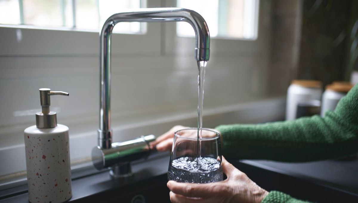Eau pure coulant d'un robinet moderne dans un verre